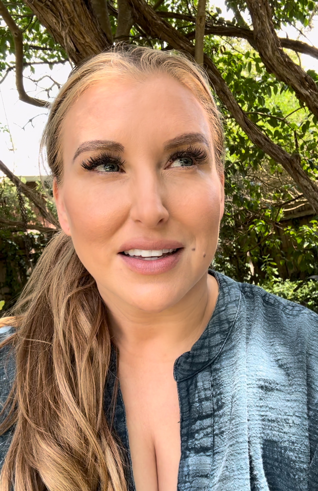 Quinn smiling in blue top with trees behind her