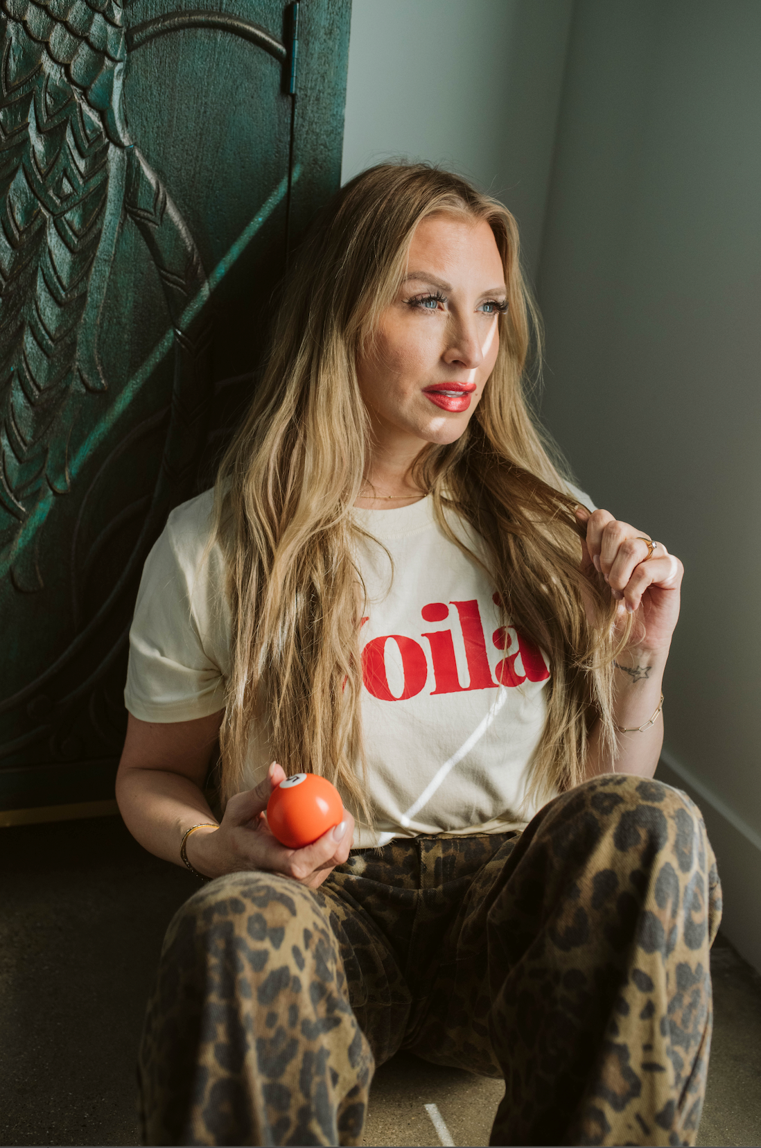Woman wearing a 'Voila' t-shirt sitting on a staircase holding an apple.